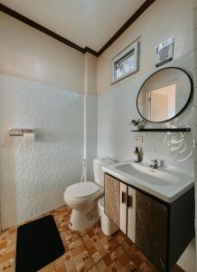 a bathroom with a toilet and a sink and a mirror at Gloria's Home Stay in Oslob