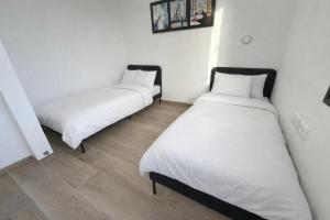 two beds in a room with white walls and wooden floors at נופי דפנה in Dafna