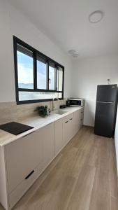a kitchen with white cabinets and a black refrigerator at נופי דפנה in Dafna