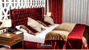 a bedroom with a large bed with a red headboard at Shams Albasra Hotel in Al Başrah