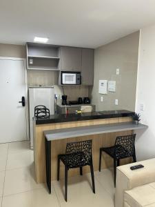 Eine Küche mit einer Bar mit zwei Stühlen und einer Theke in der Unterkunft Studio Design 310 in Sobral