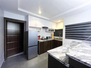 a kitchen with a stainless steel refrigerator and a counter at Deluxe Indulgence Hotel & Suites in Abuja