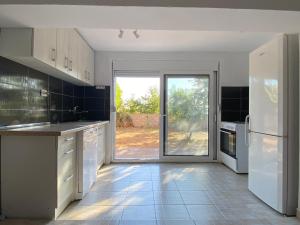 a kitchen with white appliances and a large sliding glass door at Pink Holiday House Sutomore in Zankovići