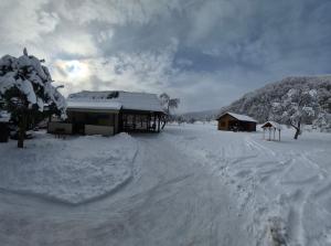 a snow covered field with a building and a house at Садиба Оберіг 2 in Sheshory