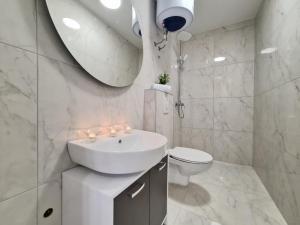 a bathroom with a sink and a toilet and a mirror at AURA Apartments Novalja in Novalja +26 photos