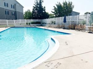 a large swimming pool with chairs and a fence at Beach perfect getaway 2 bedroom apartment in Rehoboth Beach