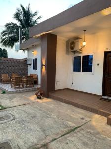 a house with a wooden porch and a patio at Hôtel Okpèyèmi in Porto-Novo
