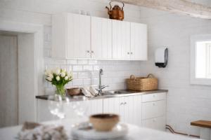 a kitchen with white cabinets and a vase of flowers on a counter at Smålandstorpets lanthotell in Hok +65 photos