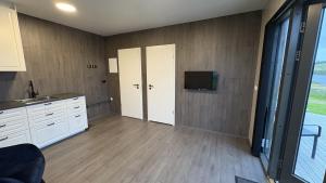 a kitchen with white cabinets and a tv on the wall at Tommutún cottages in Borgarnes