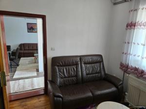 a leather couch in a living room with a mirror at Konak Kragujevac in Kragujevac