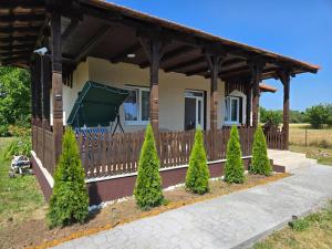 a house with a porch with a fence and trees at Konak Kragujevac in Kragujevac