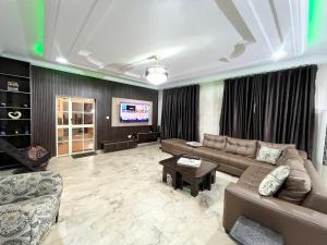 a living room with a couch and a tv at Deluxe Indulgence Hotel & Suites in Abuja