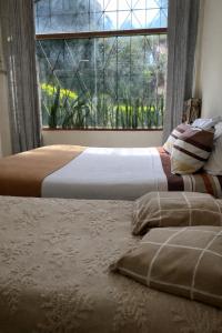two beds in a bedroom with a large window at Apartamento en zona centro de Asunción - tranquilo y con acceso directo in Asunción