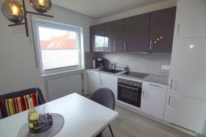 a kitchen with white cabinets and a table and a window at Stadtlounge Norden in Norden