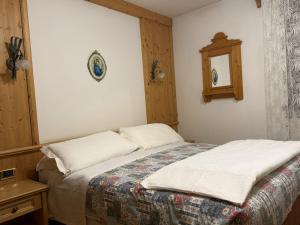 a bedroom with a bed and a mirror on the wall at Campiglio Trilocale Dolomiti in Madonna di Campiglio