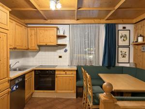a kitchen with wooden cabinets and a table with chairs at Campiglio Trilocale Dolomiti in Madonna di Campiglio