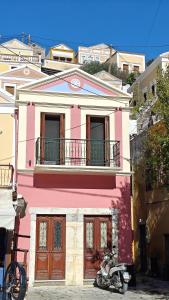 a pink house with a motorcycle parked in front of it at Main square apartment in Symi