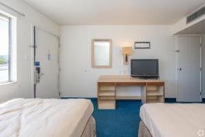 a room with two beds and a desk with a television at Gazelle Stay by Hotel O Socorro in Socorro