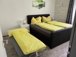 two beds with yellow sheets in a room at Papillon in Saas-Grund