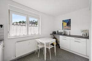 a white kitchen with a table and a window at Worker Place Lennestadt in Lennestadt +3 photos
