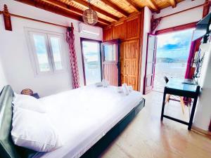 a bedroom with a bed and a desk and a window at Villa Vasilis in Mikonos