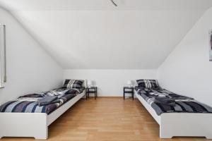 two beds in a room with white walls and wooden floors at Cosy Worker Apartment Olpe in Olpe