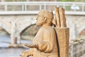 a wooden statue sitting next to a bridge at Riverside Holiday in Eupen