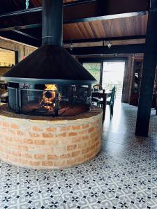 a large brick fireplace in a room with a table at LA PIANTA - Seu refúgio na Vila de Monte Verde in Monte Verde