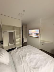 a bedroom with a large white bed with a tv on the wall at Perfect Place 32 in Varaždin