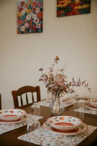 a dining room table with plates and flowers in a vase at La Casetta - un piccolo angolo di pace in Piccianello