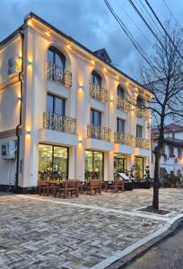 a large white building with benches in front of it at Alko Hotel Shkoder in Shkodër