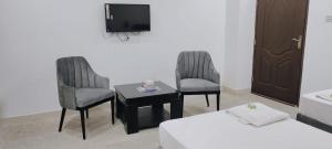 a room with two chairs and a table and a tv at Hotel Golden in Lahore