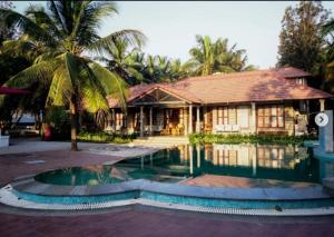 a house with a palm tree next to a pool at Mandala Resort in Sondekoppa