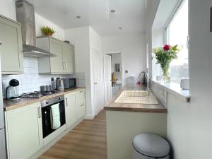a kitchen with white cabinets and a vase of flowers at HNFC Stays - Shoreline Flat in South Shields