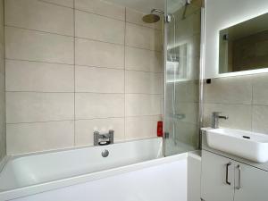 a bathroom with a white tub and a sink at HNFC Stays - Shoreline Flat in South Shields +2 photos
