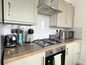 a kitchen with white cabinets and a stove top oven at HNFC Stays - Shoreline Flat in South Shields
