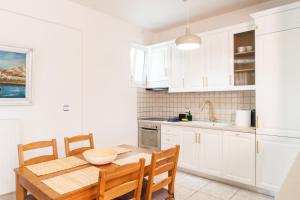 a kitchen with white cabinets and a table and chairs at Dimeli 3 in Litochoro