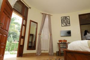 a bedroom with a bed and a mirror and a television at Forest Park Resort in Buloba