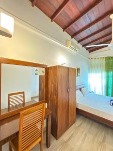 a bedroom with a bed and a wooden cabinet and a desk at Dew Ceylon Villa Negombo in Negombo