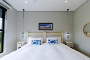 a bedroom with a large white bed with blue pillows at Husk 17 - Sheffield Beach in Ballito +2 photos