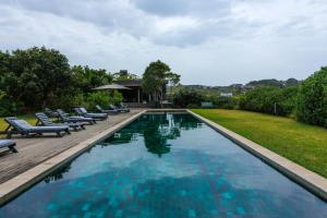 a large swimming pool with lounge chairs next to a yard at Husk 17 - Sheffield Beach in Ballito