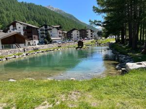 a river in the middle of a town with buildings at Papillon in Saas-Grund
