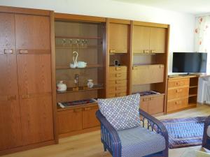 a room with wooden cabinets and a chair and a television at FEWO Weber in Lukowitz