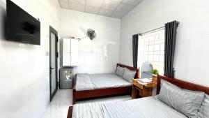 a small room with two beds and a window at Nhà Nghỉ Như Ý in Phan Rang–Tháp Chàm
