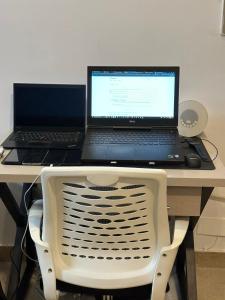 two laptops sitting on a desk with a chair at AuraStays in Dargai