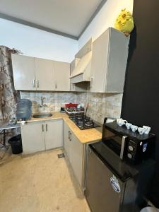 a kitchen with white cabinets and a stove top oven at AuraStays in Dargai