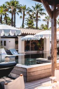 a pool with an umbrella and chairs and palm trees at Kon Tiki in Saint-Tropez