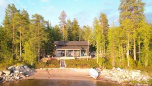 a house on the shore of a body of water at Kettula Getaway - Sauna Cabin in Suomussalmi