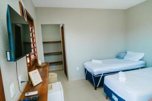 a room with two beds and a flat screen tv at Chalé sol de Macapá 1- Refúgio Pertinho do Mar in Luis Correia
