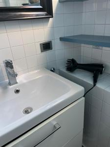 a bathroom with a white sink and a black brush at Relax Luino vista lago Casa LEA in Luino